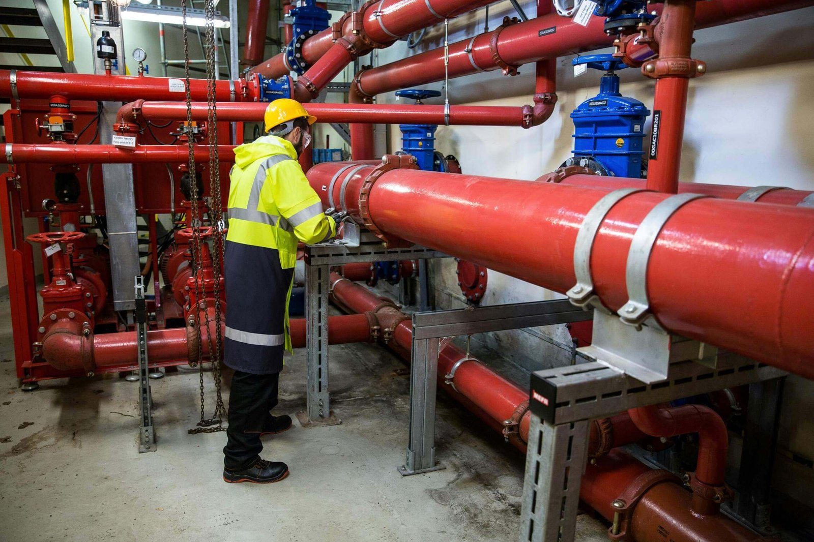 A commercial plumbing job. Man working on large pipes.