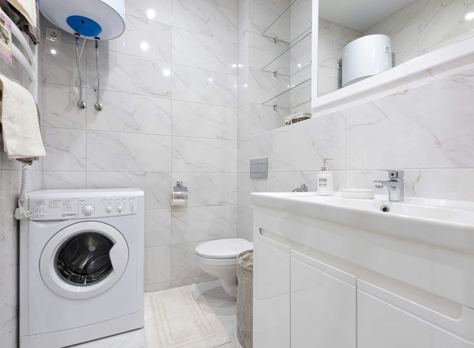 White bathroom with toilet, bath and washer.